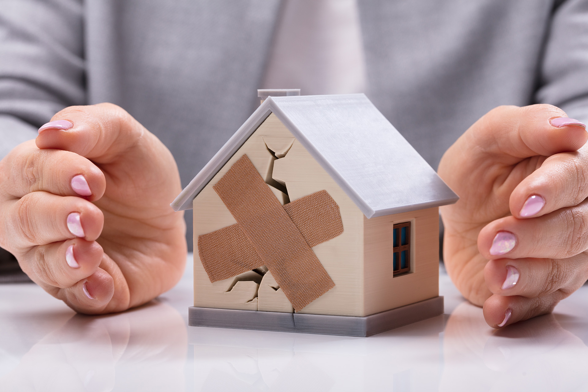 Model house with large crack covered with bandaid.